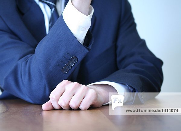 Midsection view of businessman sitting at table in office