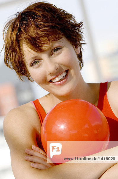 Porträt einer jungen Frau mit rotem Ball  lächelnd für die Kamera