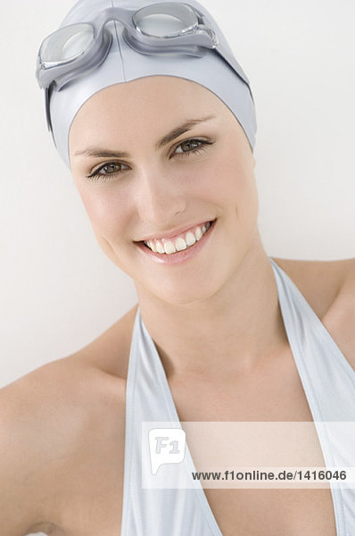 Portrait of a young smiling woman with bikini  swimming cap and goggles