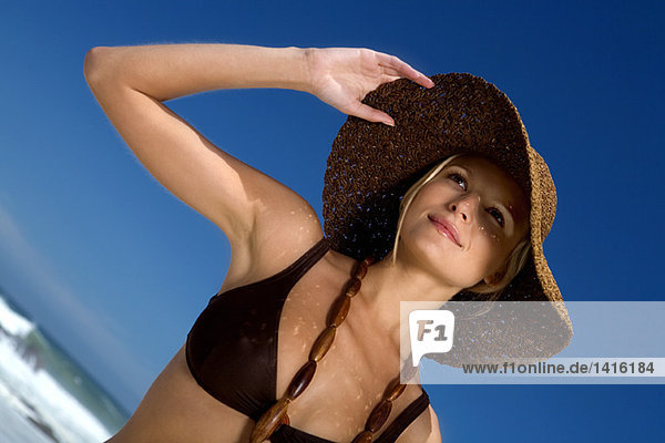 Junge Frau im Bikini am Strand  Hut und Halskette