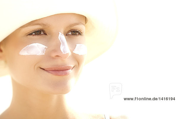 Portrait einer jungen Frau mit Sonnencreme im Gesicht