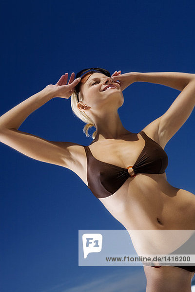 Junge lächelnde Frau im Bikini am Strand  Sonnenbrille