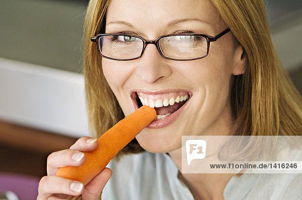 Portrait of a woman biting carrot