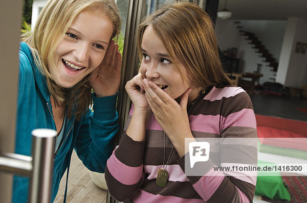 2 smiling teenage girls using mobile phone