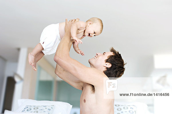 Father and baby playing  man lifting his son  indoors