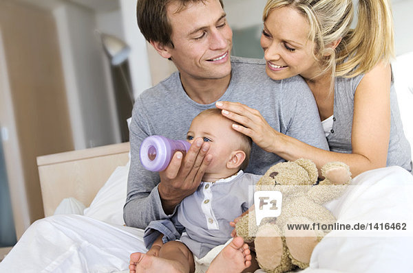 Junges Paar und Baby im Wohnzimmer  Vater füttert seinen Sohn  drinnen