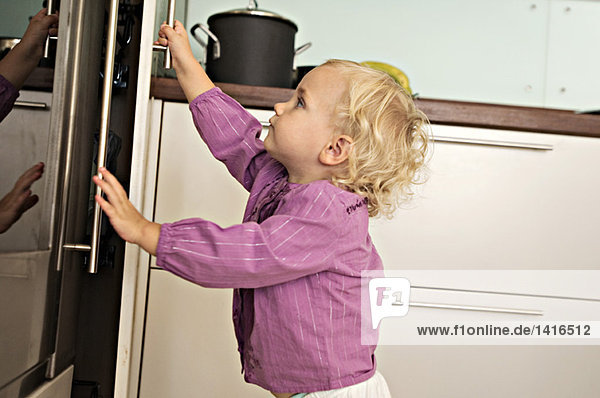 Littel girl opening fridge  indoors