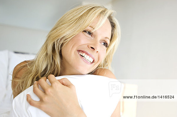 Portrait of young woman smiling  holding pillow  indoors