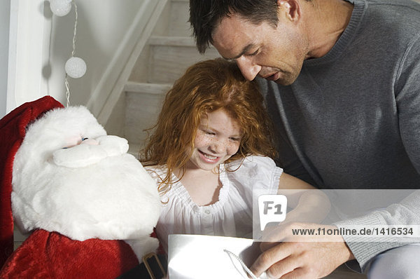 Vater und Tochter eröffnen Weihnachtsgeschenke  drinnen