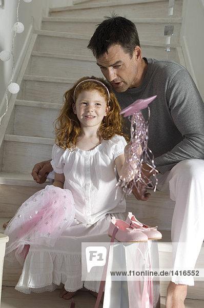 Vater und Tochter mit Weihnachtsgeschenken  Mädchen im Prinzessinnenkostüm  drinnen
