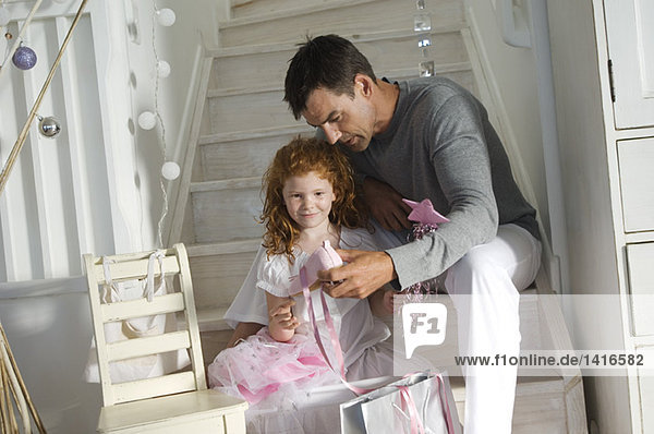 Vater und Tochter eröffnen Weihnachtsgeschenke  Mädchen im Prinzessinnenkostüm  drinnen