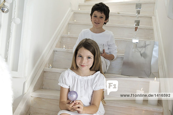 Little girl sitting indoors  holding a Christmas ball