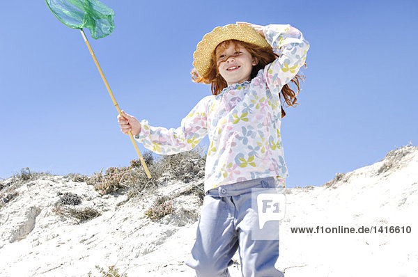 Little girl walking on the beach  holding a landing net  outdoors
