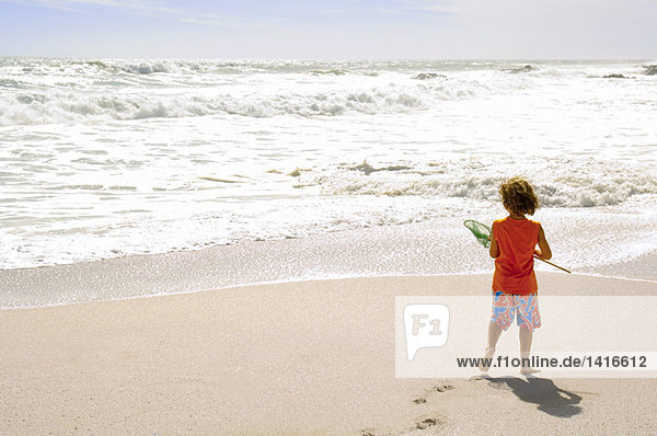 Little boy on the beach holding a landing net  outdoors