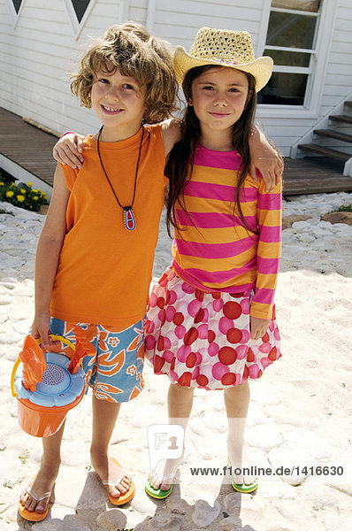 Little boy and little girl looking at the camera  in front of a house  outdoors