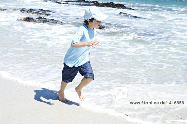 Junge läuft am Strand  im Freien