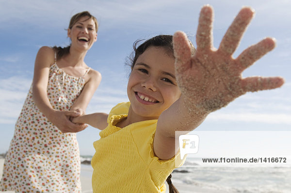 Mutter und Tochter am Strand  Mädchen streckt ihre Hand aus  im Freien