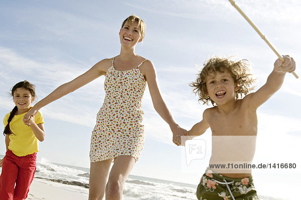 Mutter und zwei Kinder beim Spaziergang am Strand  im Freien