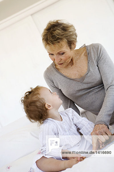Senior woman with little girl on bed