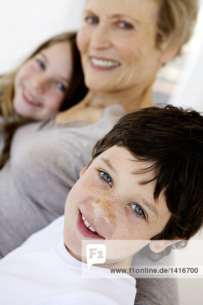 Senior woman and two children smiling for the camera  indoors