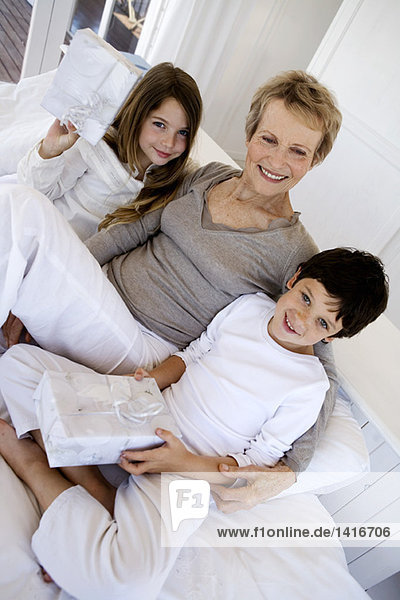 Senior woman and two children holding gifts  indoors