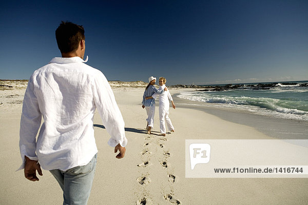 Paar und Seniorin beim Spaziergang am Strand