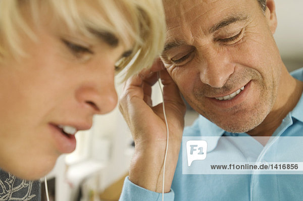 Porträt eines Vaters und seines Sohnes beim Hören eines MP3-Players  drinnen