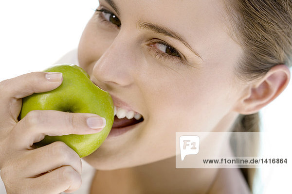 Porträt einer jungen Frau  die einen Apfel isst  drinnen