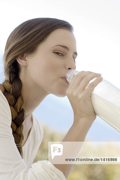 Porträt einer jungen Frau  die Milch aus der Flasche trinkt  im Freien