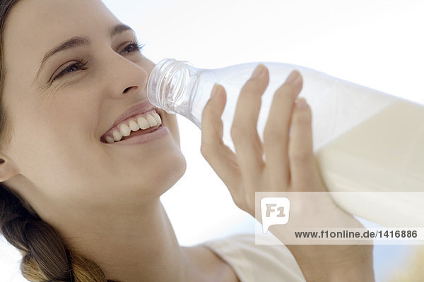 Porträt einer jungen Frau  die Milch aus der Flasche trinkt  im Freien