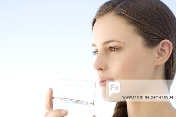 Porträt einer jungen Frau  die ein Wasserglas hält  im Freien