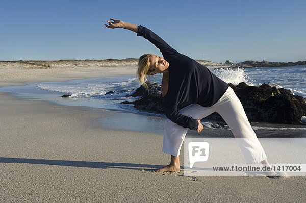 Young woman stretching on the beach  outdoors