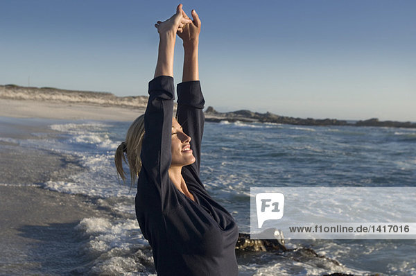 Young woman on the beach  stretching  outdoors