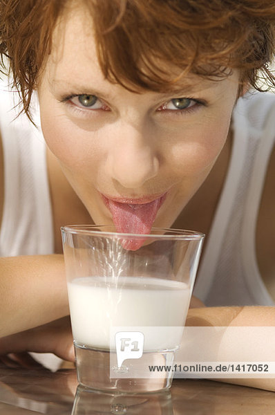 Porträt einer jungen Frau  die Milch aus einem Glas leckt