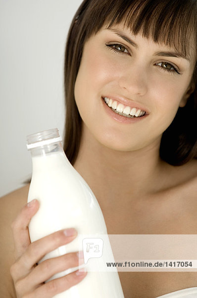 Porträt einer jungen lächelnden Frau mit Milchflasche