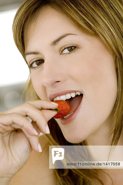 Porträt einer jungen Frau beim Essen einer Erdbeere