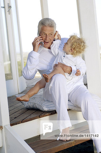 Senior man using mobile phone  with little boy