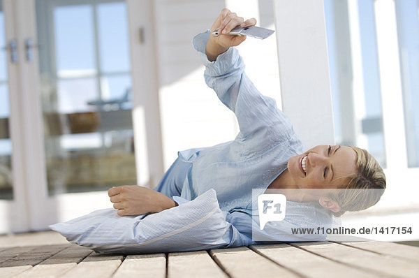 Young woman lying on floor  using mobile phone