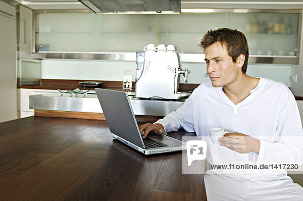Young man using laptop in kitchen