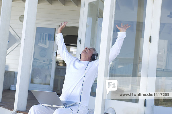 Man listening to music with laptop  arms in the air