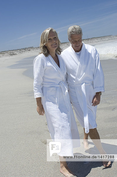 Paar im Bademantel am Strand spazieren gehen
