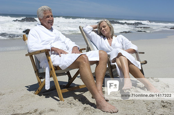 Paar im Bademantel  auf Strandkörben sitzend
