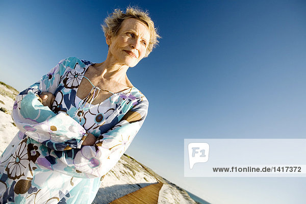 Senior woman with arms crossed at seaside