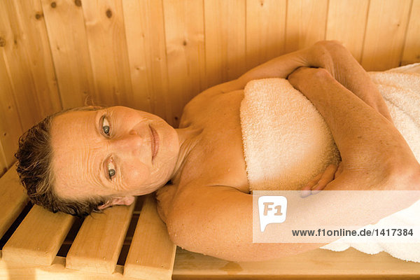 Senior woman lying in sauna