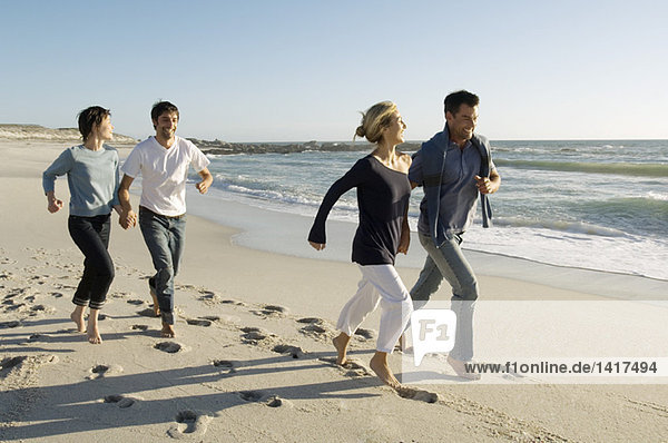 2 Paare  die am Strand laufen