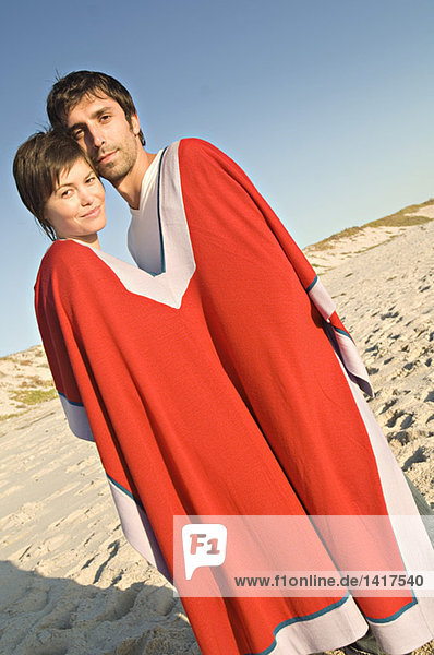 Ein Paar am Strand  das sich einen Poncho teilt.