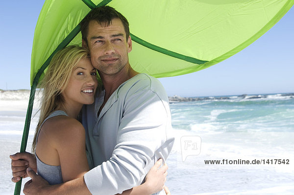 Couple embracing on the beach  beach umbrella