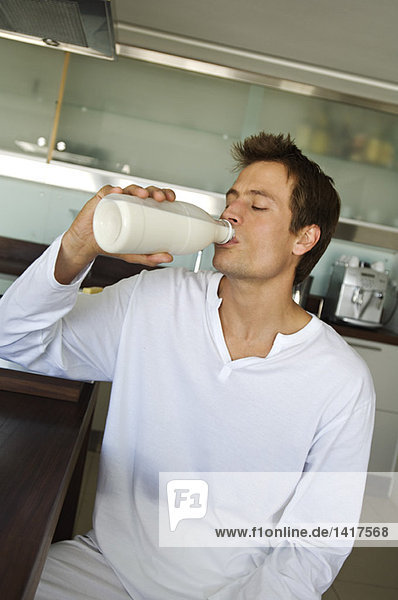 Junger Mann trinkt Milch aus der Flasche