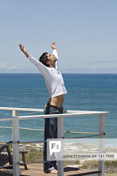 Junger Mann auf der Terrasse  Meer im Hintergrund