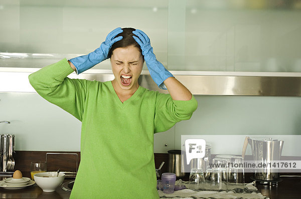 Junge Frau schreit in der Küche  Hände auf dem Kopf